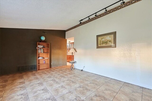 unfurnished room with a textured ceiling and lofted ceiling