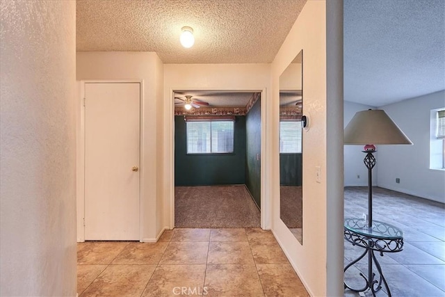 hall with a textured ceiling and light tile patterned flooring