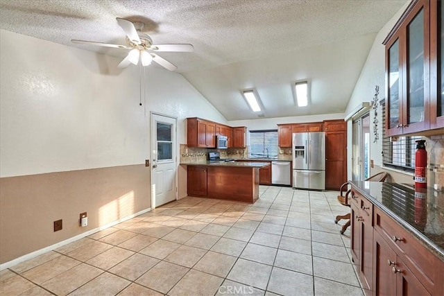 kitchen featuring vaulted ceiling, stainless steel appliances, tasteful backsplash, light tile patterned flooring, and ceiling fan