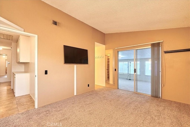 carpeted empty room featuring vaulted ceiling and a textured ceiling