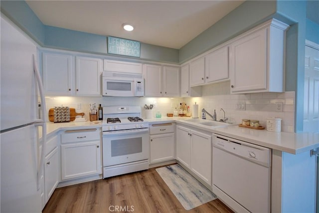 kitchen featuring white cabinetry, tasteful backsplash, white appliances, light hardwood / wood-style flooring, and sink