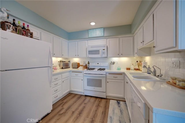 kitchen with white cabinetry, light hardwood / wood-style floors, decorative backsplash, white appliances, and sink