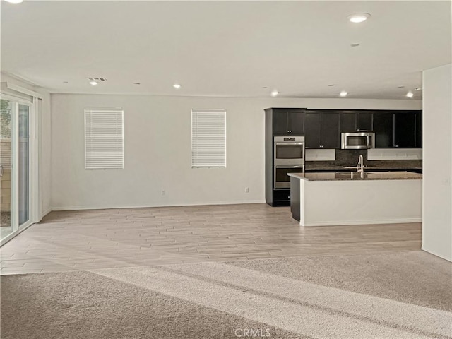 unfurnished living room featuring sink and light hardwood / wood-style floors