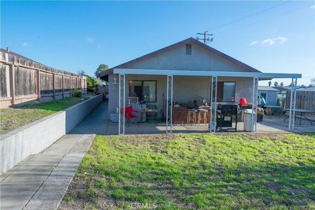 back of house with a patio area and a lawn