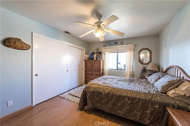 bedroom with hardwood / wood-style floors, ceiling fan, and a closet