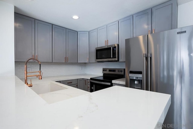 kitchen featuring decorative backsplash, sink, kitchen peninsula, and stainless steel appliances