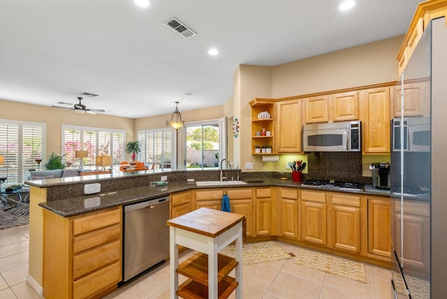 kitchen featuring stainless steel appliances, decorative backsplash, sink, kitchen peninsula, and ceiling fan