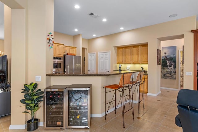 kitchen featuring stainless steel appliances, wine cooler, kitchen peninsula, and dark stone counters