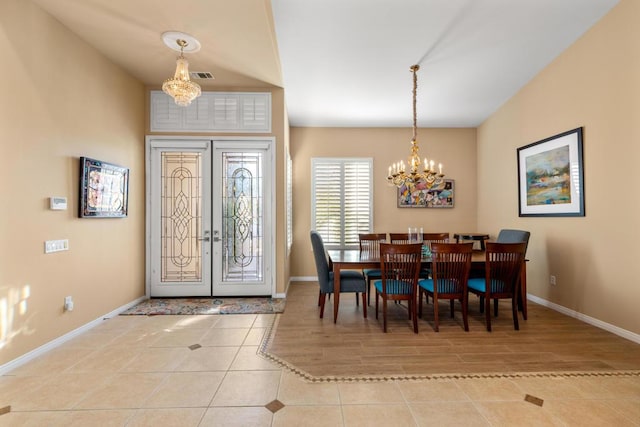 foyer entrance with light tile patterned floors, french doors, and a notable chandelier