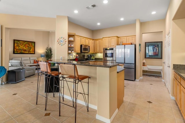 kitchen with kitchen peninsula, a kitchen bar, appliances with stainless steel finishes, light brown cabinets, and light tile patterned floors