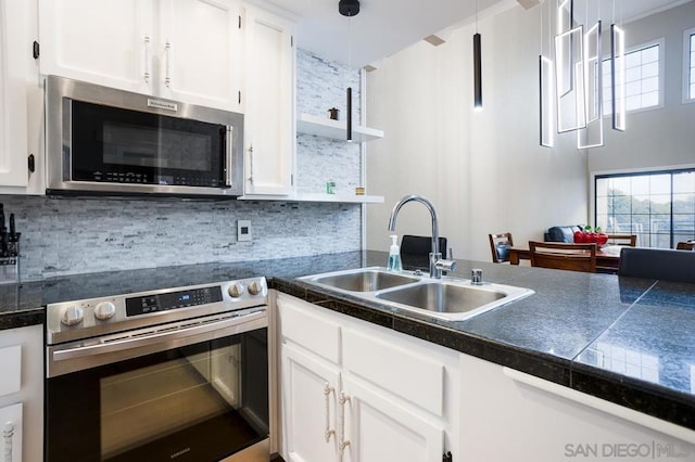 kitchen featuring white cabinetry, decorative backsplash, sink, hanging light fixtures, and wall oven