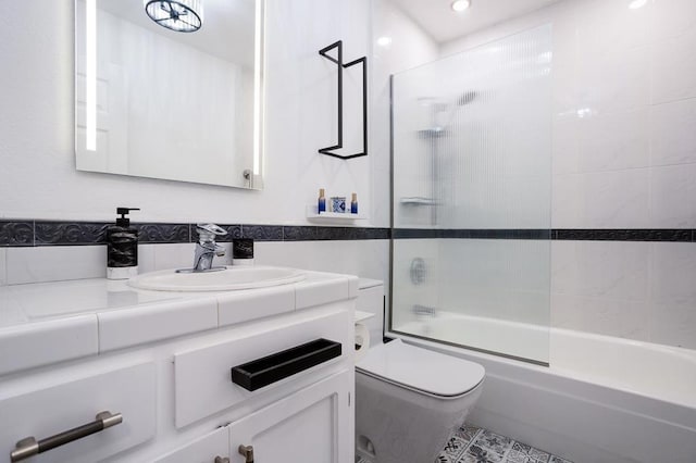 full bathroom featuring toilet, vanity, tile walls, and shower / bath combination with glass door