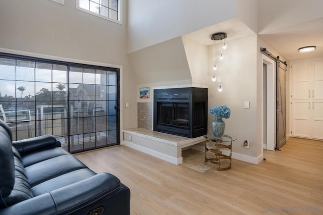 living room with hardwood / wood-style flooring, a multi sided fireplace, and a barn door