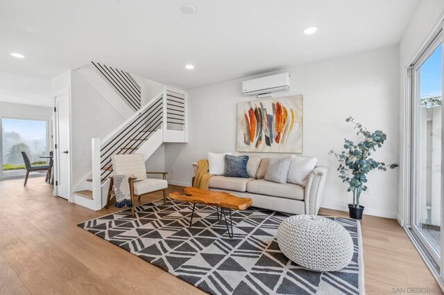 living room with light hardwood / wood-style floors, a wealth of natural light, and a wall mounted AC