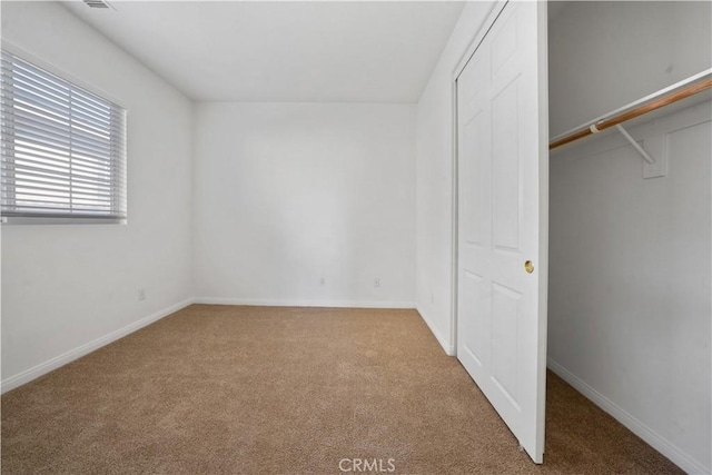 unfurnished bedroom with light colored carpet and a closet