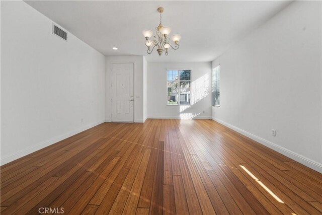 unfurnished living room featuring a chandelier and hardwood / wood-style floors