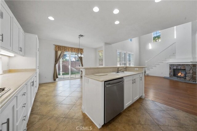 kitchen with a center island with sink, pendant lighting, dishwasher, and white cabinets