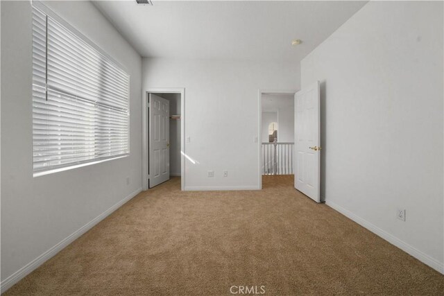 unfurnished bedroom featuring a walk in closet and light carpet