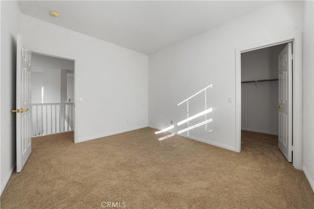 unfurnished bedroom with a walk in closet, a closet, and light colored carpet