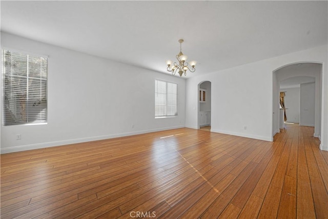 empty room with plenty of natural light, light hardwood / wood-style flooring, and a notable chandelier