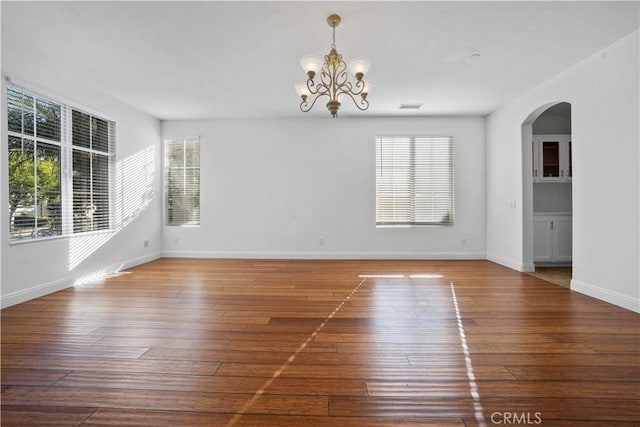 spare room with wood-type flooring and a notable chandelier