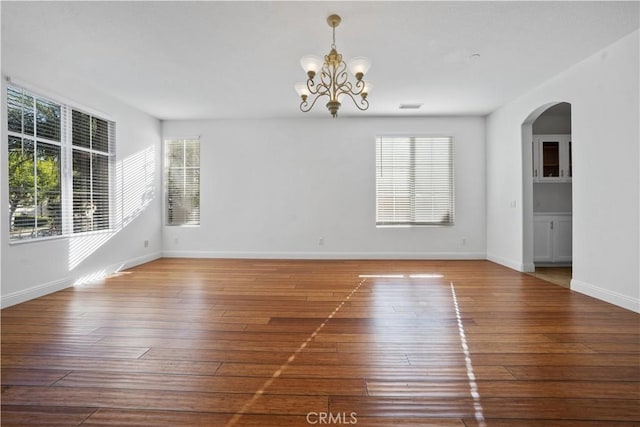 empty room featuring wood-type flooring and a notable chandelier