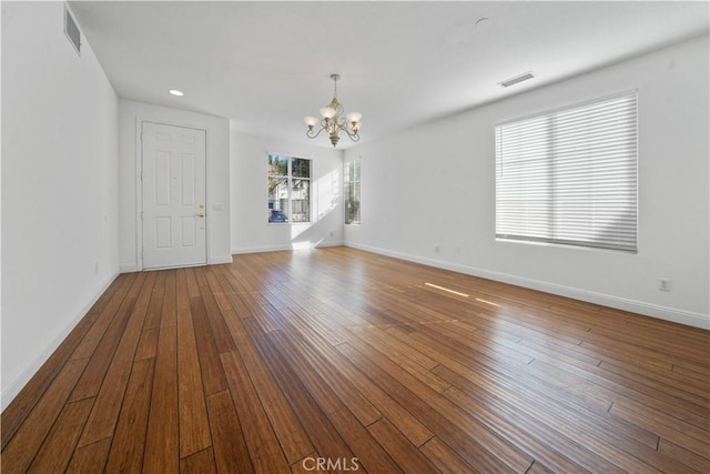 spare room featuring wood-type flooring and an inviting chandelier