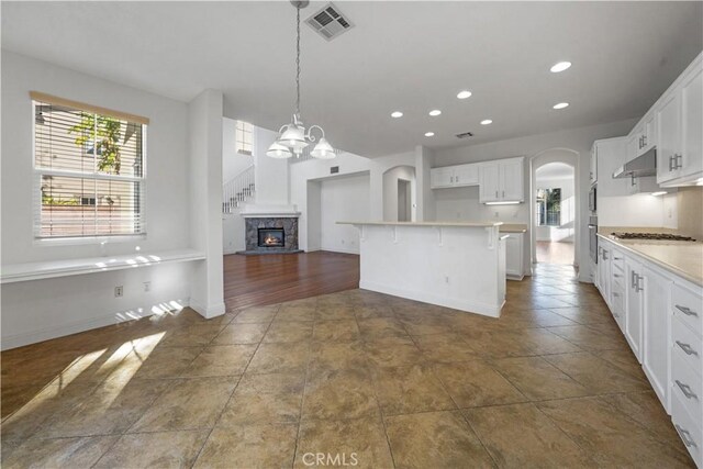 kitchen featuring white cabinetry, decorative light fixtures, a kitchen breakfast bar, a chandelier, and a center island