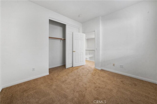 unfurnished bedroom featuring a closet and light carpet