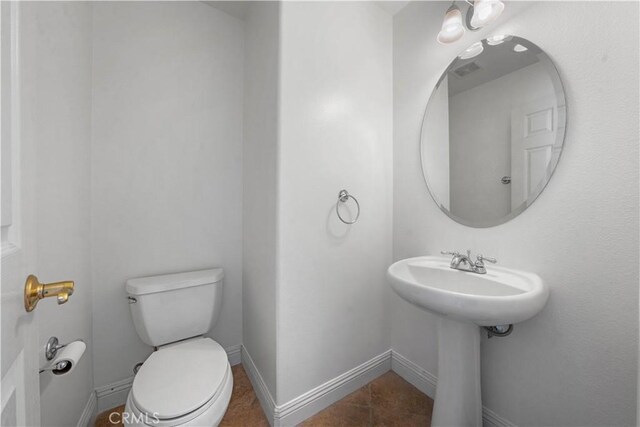 bathroom with toilet, tile patterned flooring, and sink