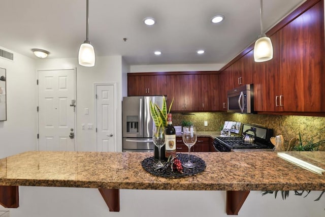 kitchen featuring decorative light fixtures, a breakfast bar area, stainless steel appliances, and kitchen peninsula