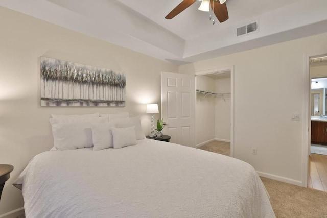 bedroom featuring light carpet, a spacious closet, a closet, and ceiling fan