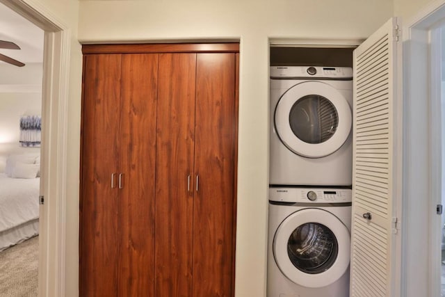 clothes washing area with stacked washer / dryer, carpet floors, and ceiling fan