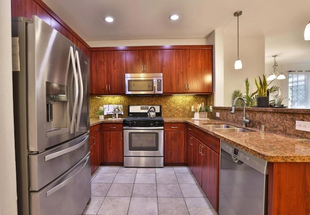 kitchen featuring appliances with stainless steel finishes, decorative light fixtures, sink, light tile patterned floors, and kitchen peninsula