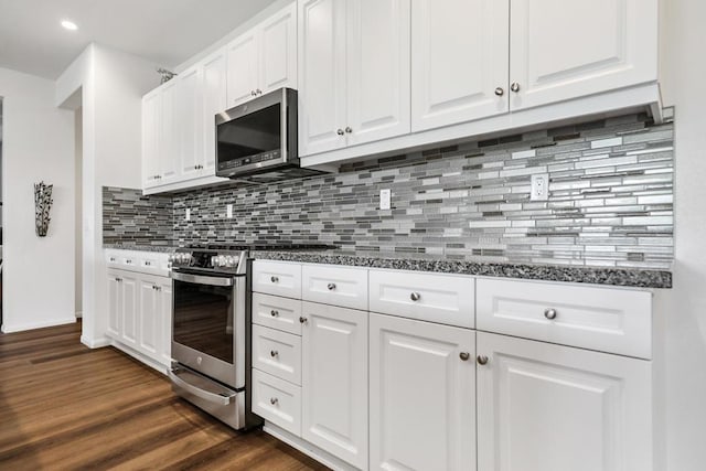 kitchen featuring white cabinetry, stainless steel appliances, dark stone counters, backsplash, and dark hardwood / wood-style floors