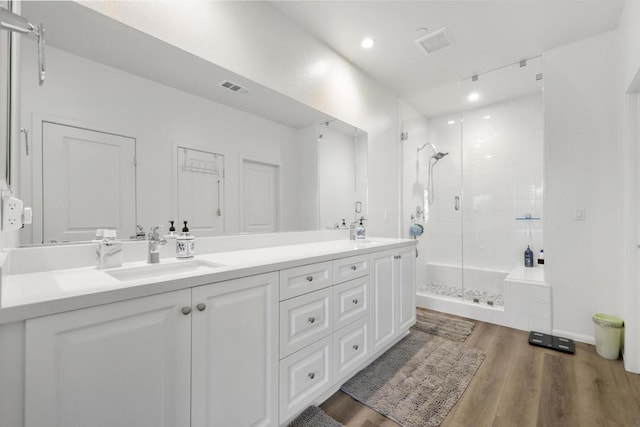 bathroom featuring hardwood / wood-style floors, a shower with door, and vanity