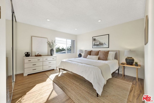 bedroom with light wood-type flooring and a textured ceiling