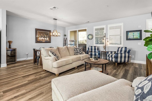 living room with beverage cooler, an inviting chandelier, and hardwood / wood-style flooring