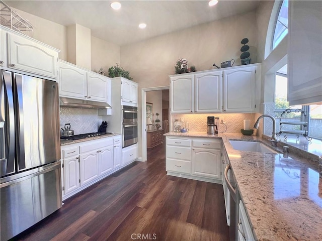 kitchen with sink, light stone counters, stainless steel appliances, and white cabinetry