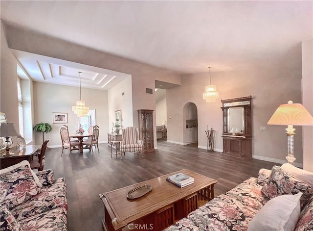 living room with a tray ceiling, dark hardwood / wood-style flooring, and an inviting chandelier