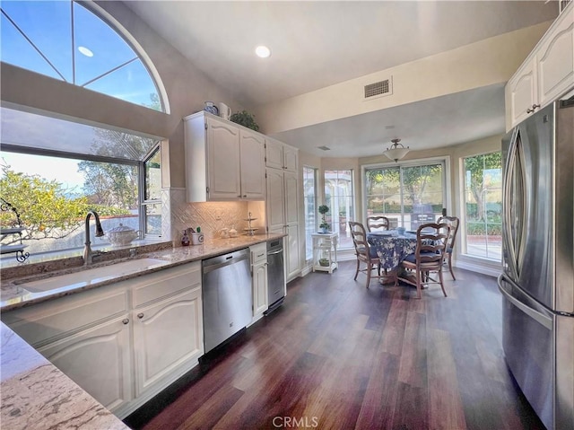 kitchen featuring light stone countertops, backsplash, white cabinets, and stainless steel appliances