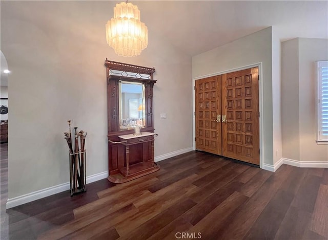 foyer entrance featuring dark wood-type flooring, lofted ceiling, and a chandelier