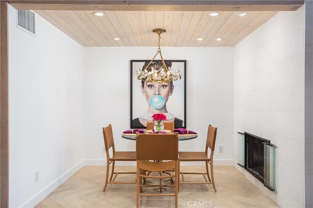 dining area with light parquet flooring, wood ceiling, a large fireplace, and a notable chandelier