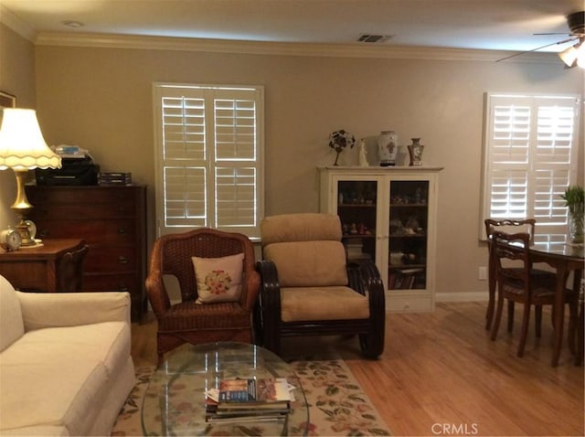 living room featuring ceiling fan, crown molding, and light wood-type flooring