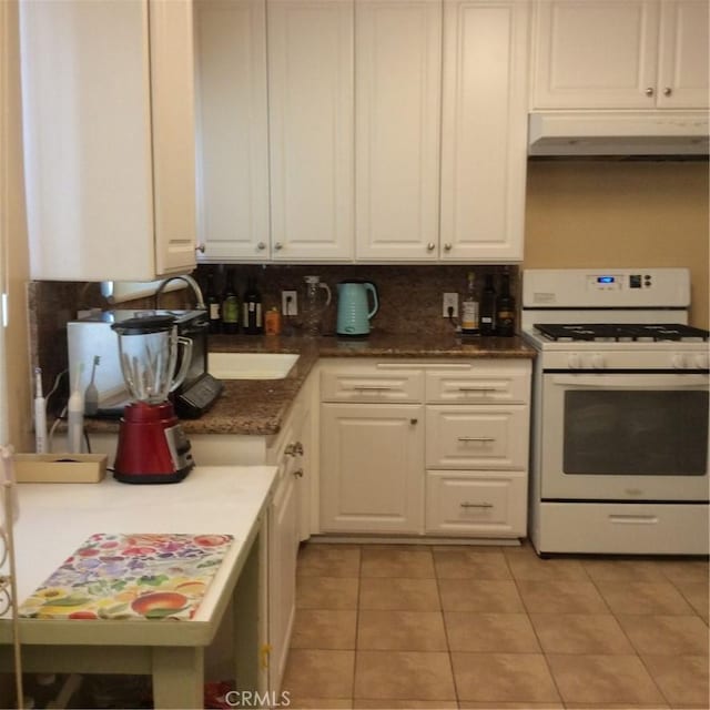 kitchen featuring decorative backsplash, white cabinetry, white gas stove, and light tile patterned flooring