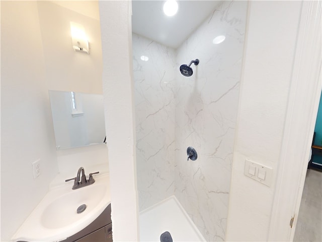 bathroom with tiled shower and vanity