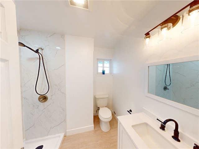 bathroom featuring toilet, a tile shower, and vanity