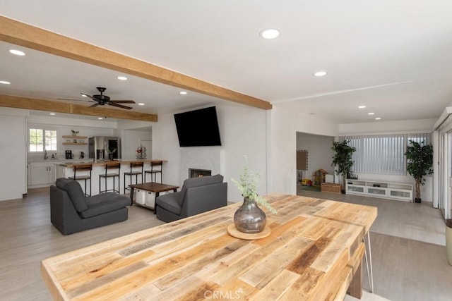 dining area with ceiling fan, beamed ceiling, and light hardwood / wood-style floors