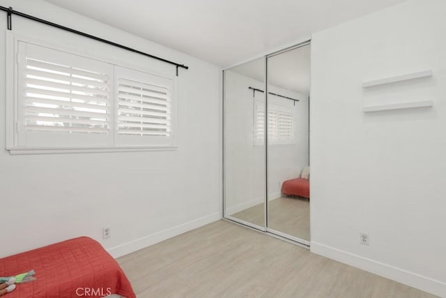 bedroom featuring a closet, light hardwood / wood-style floors, and multiple windows