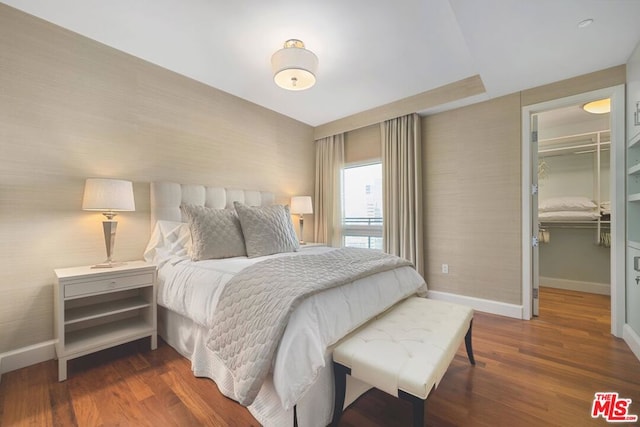 bedroom with a spacious closet, dark hardwood / wood-style floors, and a closet